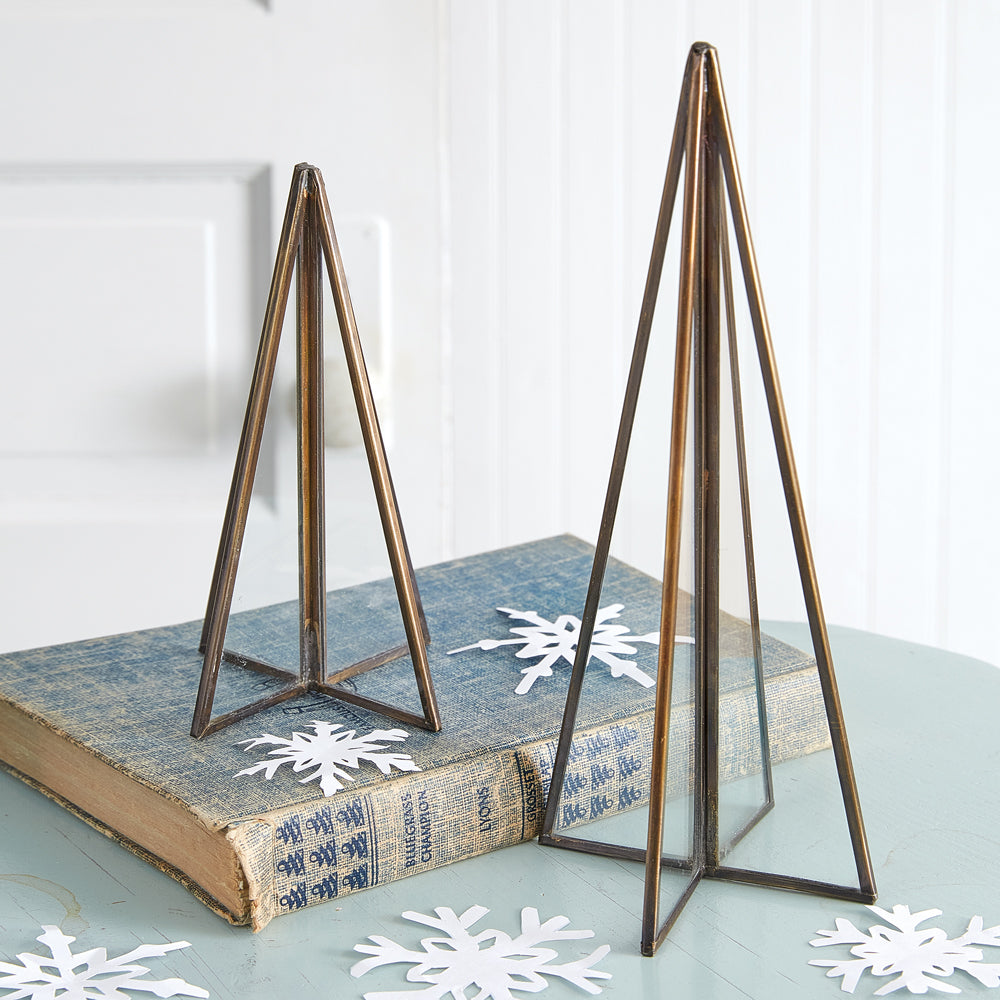 Two elegant tabletop Christmas trees with sleek brass edges and glass panels, adding a modern touch to holiday decor.