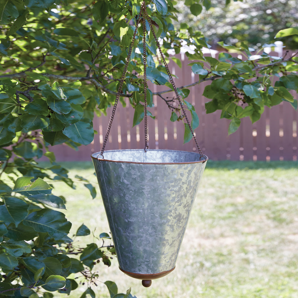 Galvanized cone planter hanging on a patio, filled with vibrant artificial flowers, adding a rustic farmhouse charm.