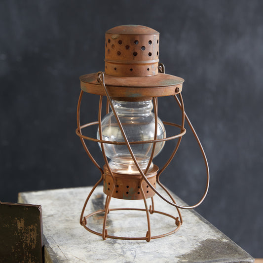 Antique railroad lantern with rustic patina finish, featuring a handle and metal base for tealight replacement, exuding vintage charm.