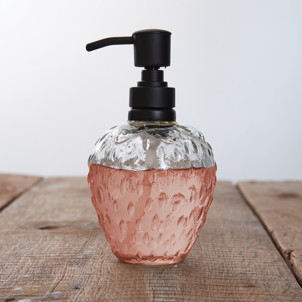 Clear glass soap dispenser shaped like a strawberry, adding a whimsical and elegant touch to kitchen or bathroom decor.