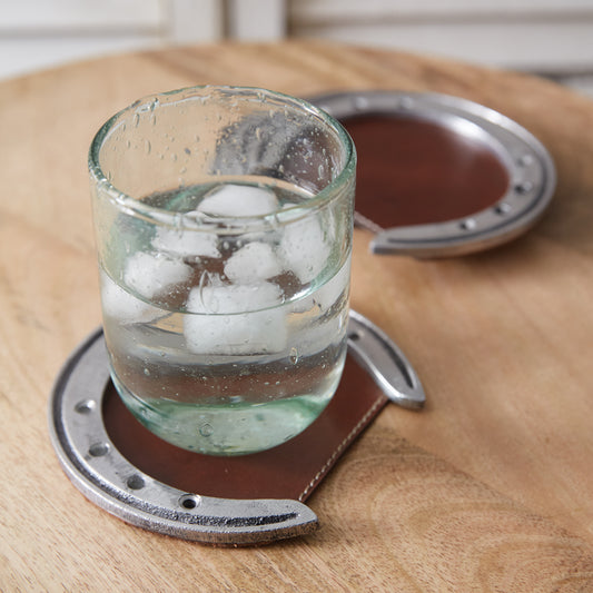 Set of four rustic coasters made from leather and aluminum horseshoes, adding a western charm to any table setting.