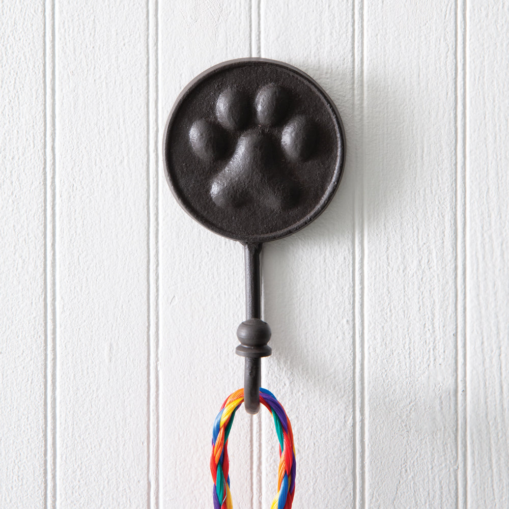 A set of four cast iron dog paw wall hooks, perfect for hanging leashes and collars, adding charm and organization to your space.