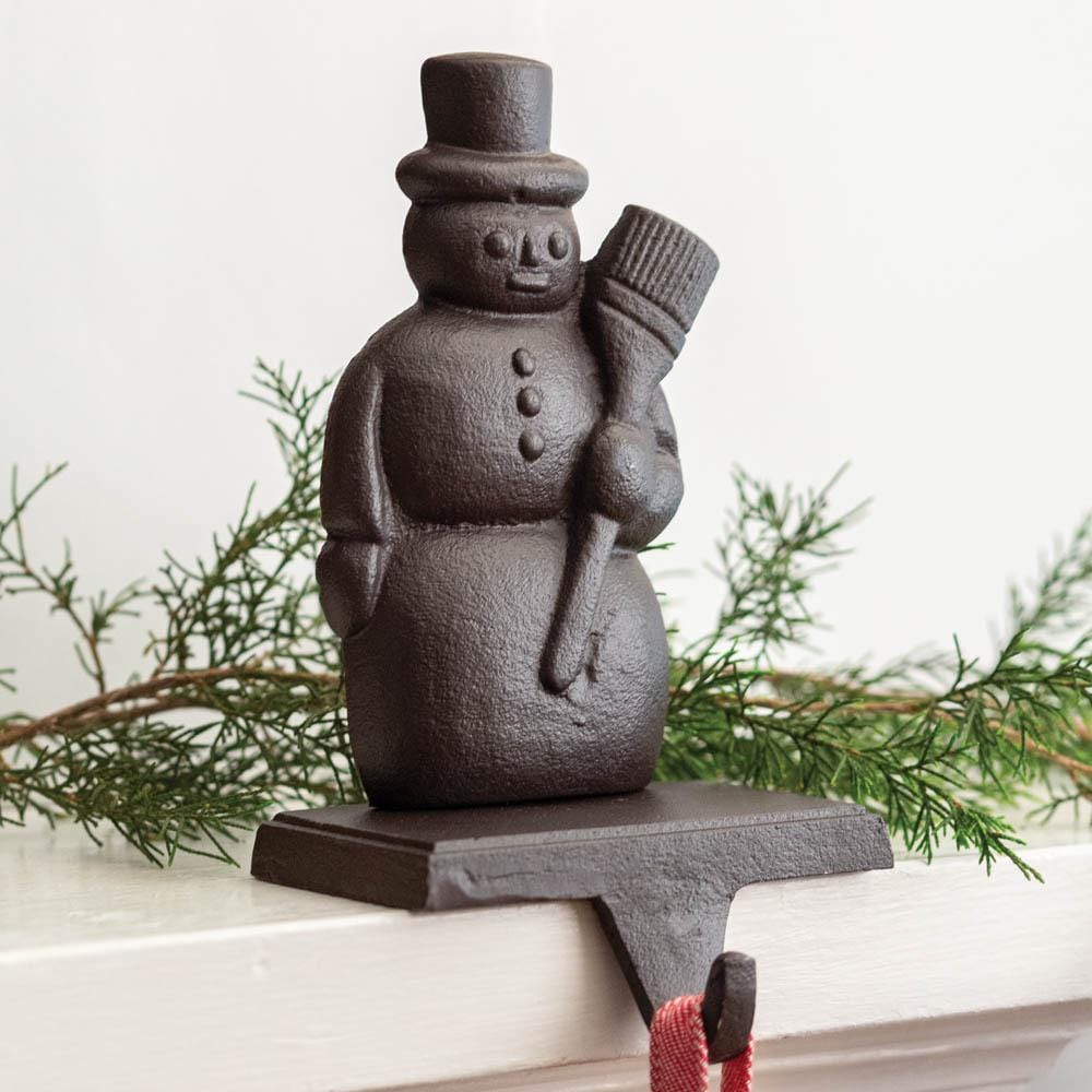 Cast iron snowman stocking holder with a rustic design, perfect for adding charm and securely holding stockings on a mantel.