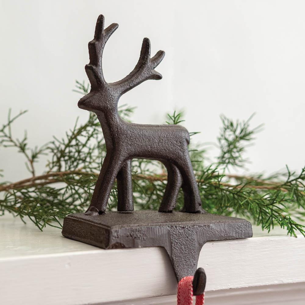 Cast iron reindeer stocking holder on a mantel, showcasing its rustic charm and sturdy design for holiday decorations.