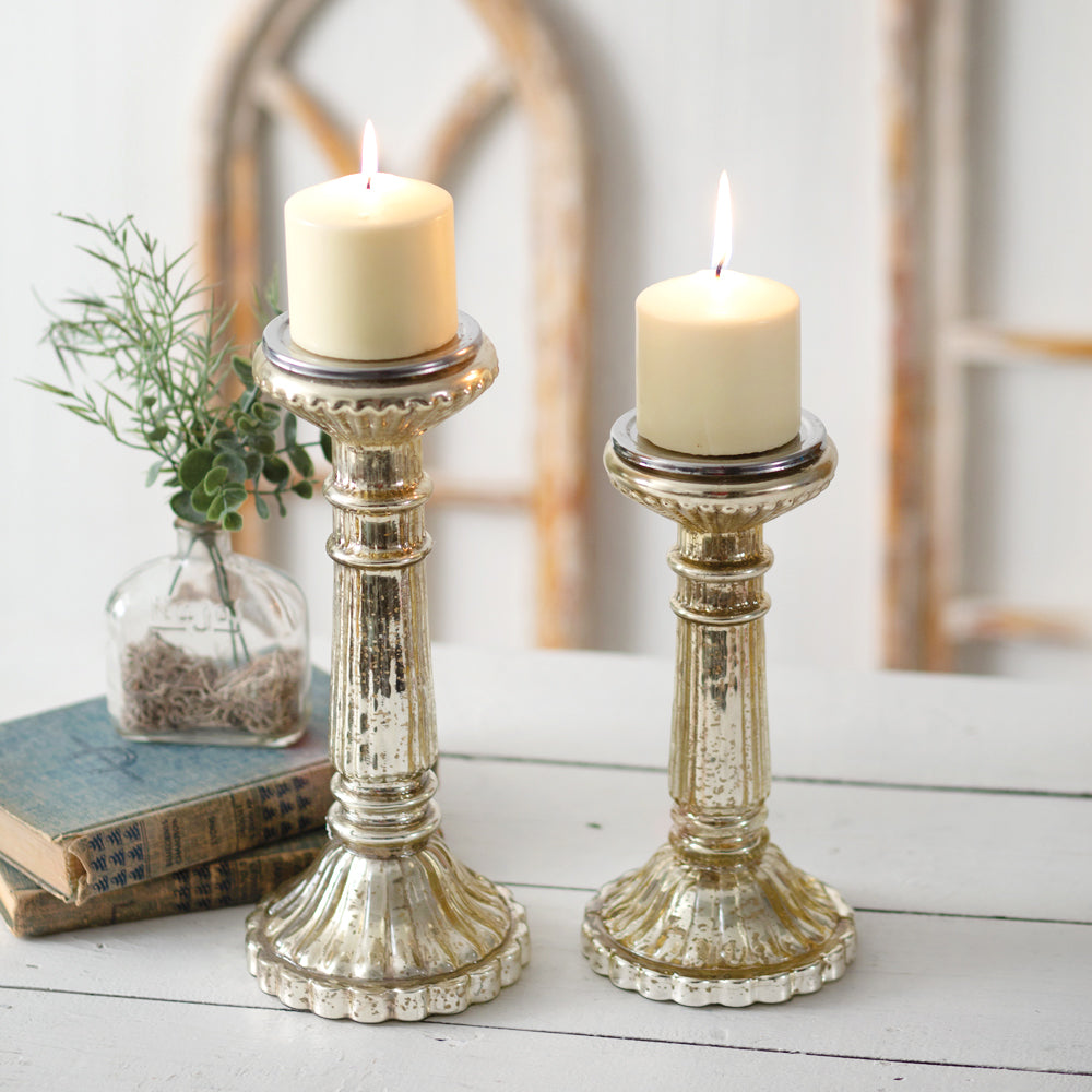 Two elegant mercury glass pillar candle holders with a gold metallic finish, perfect for adding a warm glow to any setting.