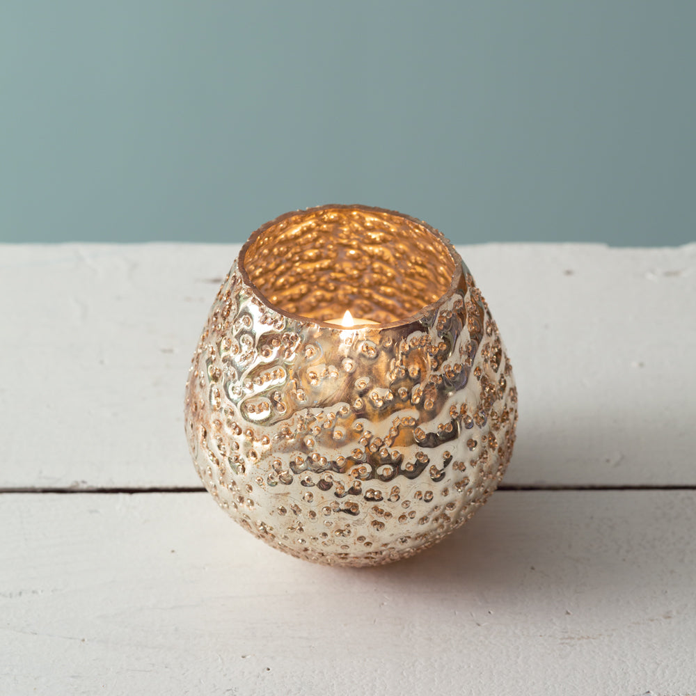 A shimmering gold mercury glass votive holder with a textured exterior, adding elegance and sparkle to any room decor.