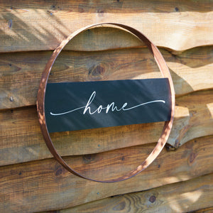 Rustic metal sign with a rusty finish, featuring the word "home" in the center, perfect for farmhouse decor.