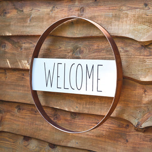 Rustic metal sign with "welcome" in the center, featuring a vintage finish, perfect for enhancing farmhouse decor.