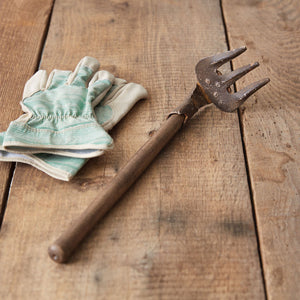 A pair of vintage hand rakes with wooden handles and metal tines, showcasing a rustic charm against a garden backdrop.