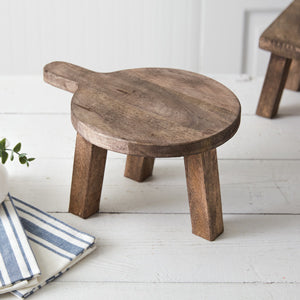 Round wooden cutting board pedestal with a rustic finish, ideal for displaying decor items, adding depth and natural elegance to spaces.