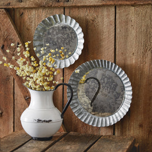 Two rustic pie tin-inspired mercury glass mirrors with galvanized metal frames, perfect for enhancing farmhouse decor.