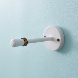 Retro metal toilet paper holder with light colors, mounted on a bathroom wall, showcasing its sturdy and stylish design.