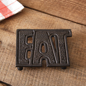 Rustic cast iron trivet with "Eat" design, perfect for farmhouse decor; adds charm and protects countertops during meals.