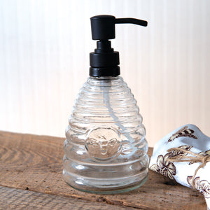 Beehive-shaped glass soap dispenser with a matte black finish, featuring a cute bee at the center, perfect for stylish decor.