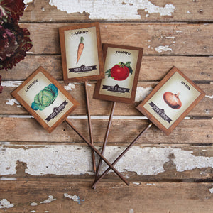 Set of four rustic vegetable markers with designs of lettuce, onions, carrots, and tomatoes, perfect for garden decor.