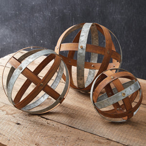 Set of three decorative mixed metal balls with rustic finishes, showcasing contemporary style and classic shapes on a wooden table.