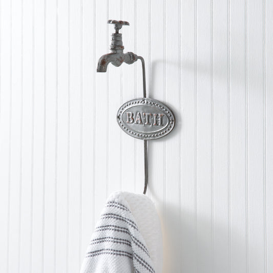 Cast iron bath hook shaped like a water faucet, mounted on a wall, perfect for hanging towels or robes in a stylish bathroom.